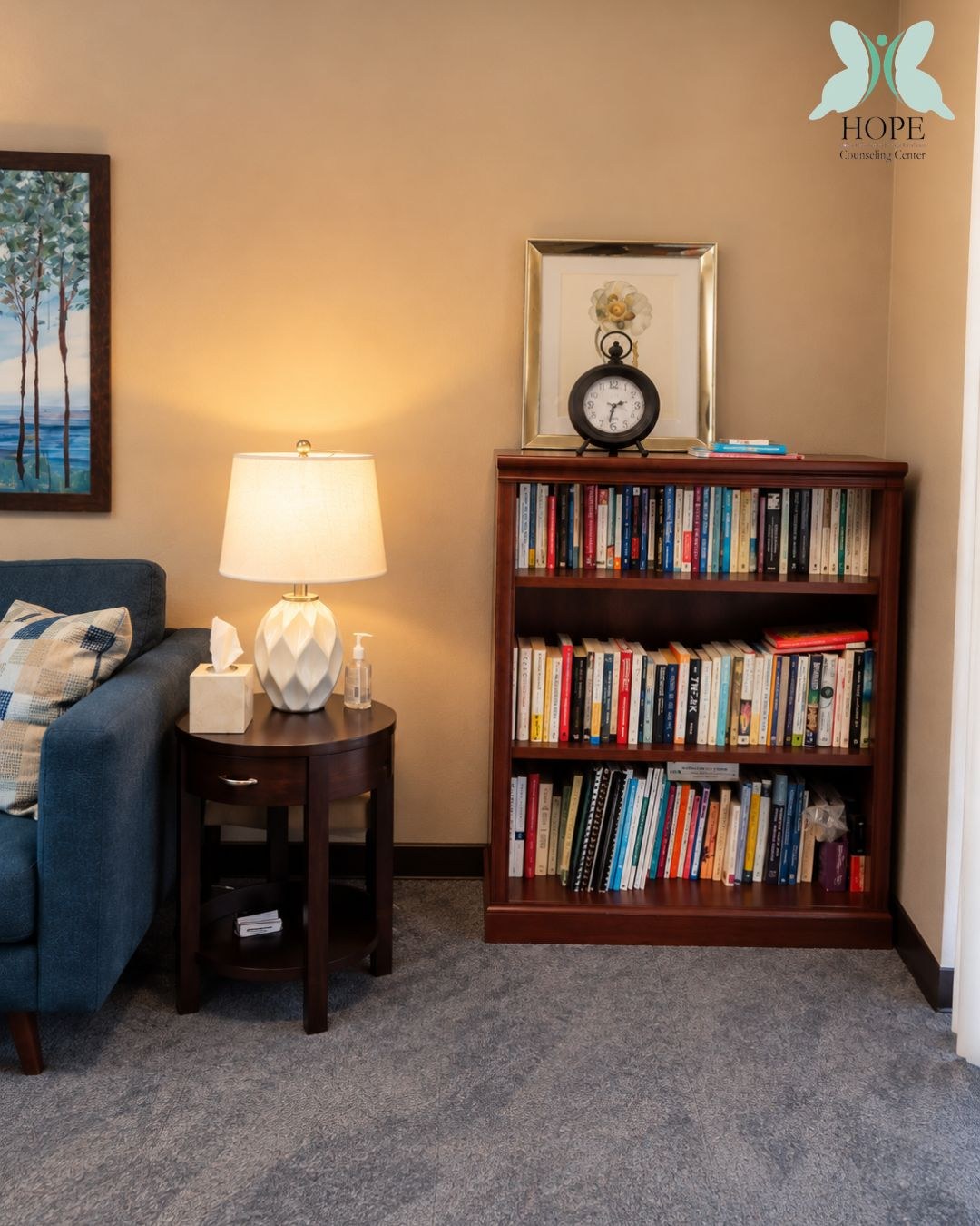 A full bookcase, a lamp and a blue armchair.