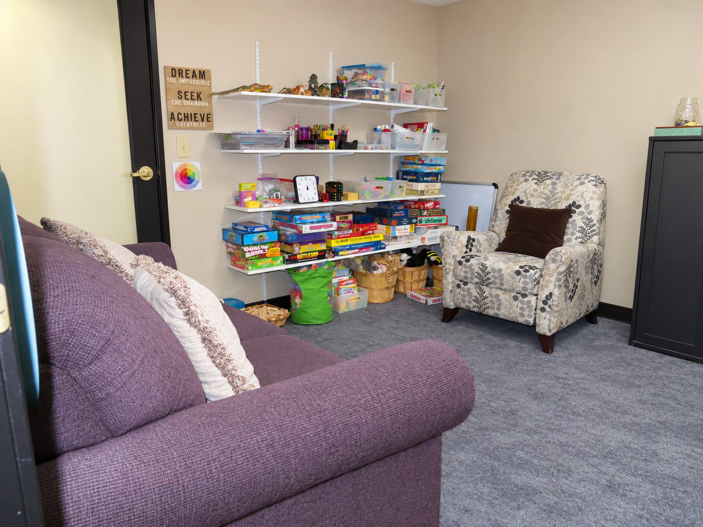 A purple sofa and shelves of toys and games for children, teens and families.